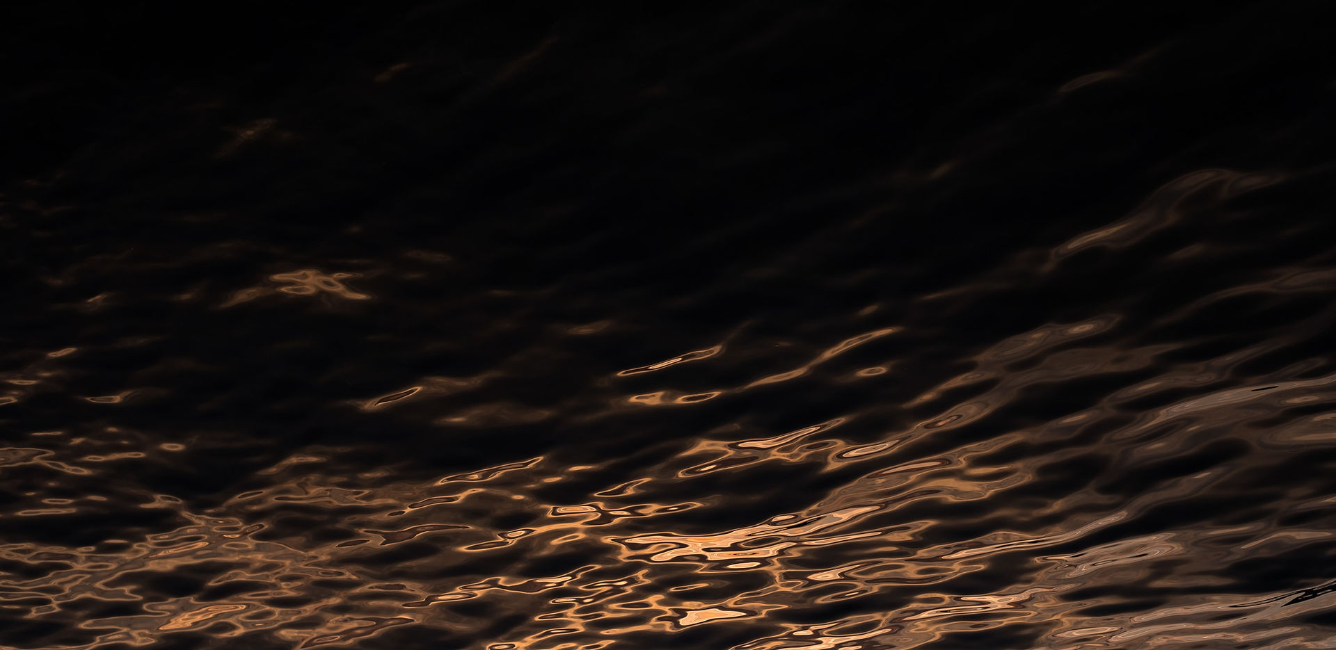Dark water reflecting molten gold light